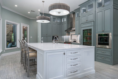 Inspiration for a large transitional u-shaped laminate floor, gray floor and vaulted ceiling eat-in kitchen remodel in Dallas with a farmhouse sink, recessed-panel cabinets, turquoise cabinets, marble countertops, white backsplash, porcelain backsplash, stainless steel appliances, an island and white countertops