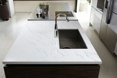Large modern galley kitchen/diner in Chicago with a submerged sink, flat-panel cabinets, white cabinets, stainless steel appliances, porcelain flooring and an island.