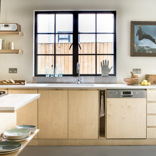 Photo of a scandinavian kitchen in Oxfordshire with a single-bowl sink, flat-panel cabinets, light wood cabinets, window splashback, integrated appliances, an island, grey floors and white worktops.