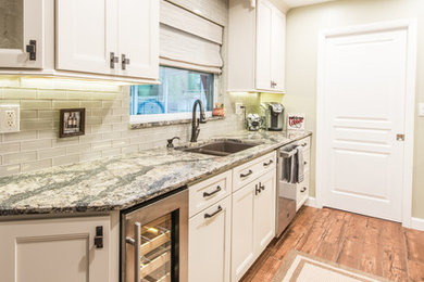 Enclosed kitchen - small transitional galley porcelain tile enclosed kitchen idea in Orlando with an undermount sink, recessed-panel cabinets, white cabinets, quartz countertops, gray backsplash, glass tile backsplash, stainless steel appliances and a peninsula