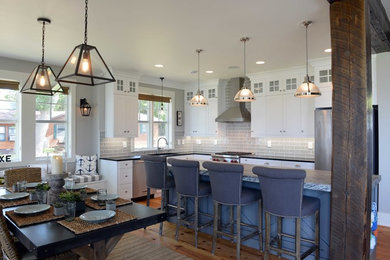 Eat-in kitchen - mid-sized transitional l-shaped light wood floor eat-in kitchen idea in Other with shaker cabinets, white cabinets, granite countertops, gray backsplash, subway tile backsplash, stainless steel appliances, an island and an undermount sink