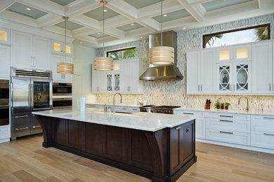 Tuscan l-shaped light wood floor kitchen photo in Miami with recessed-panel cabinets, white cabinets, multicolored backsplash, stainless steel appliances, an island and mosaic tile backsplash