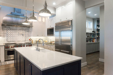 Example of a large classic u-shaped light wood floor and brown floor eat-in kitchen design in Boise with a farmhouse sink, shaker cabinets, white cabinets, marble countertops, multicolored backsplash, ceramic backsplash, stainless steel appliances and an island