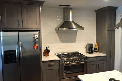 Inspiration for a large transitional u-shaped eat-in kitchen remodel in Orlando with gray cabinets, solid surface countertops, white backsplash, an island and white countertops