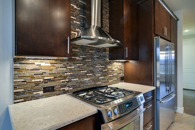 This is an example of a traditional u-shaped kitchen/diner in Other with a submerged sink, flat-panel cabinets, dark wood cabinets, engineered stone countertops, brown splashback, mosaic tiled splashback, stainless steel appliances, ceramic flooring and a breakfast bar.