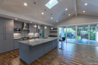 Inspiration for a mid-sized transitional galley laminate floor and brown floor open concept kitchen remodel in San Francisco with an undermount sink, shaker cabinets, gray cabinets, quartzite countertops, gray backsplash, glass tile backsplash, stainless steel appliances and an island