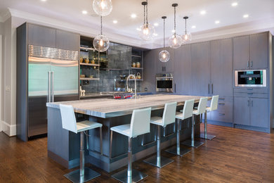 Inspiration for a large transitional l-shaped medium tone wood floor eat-in kitchen remodel in Atlanta with a farmhouse sink, flat-panel cabinets, gray cabinets, marble countertops, metallic backsplash, metal backsplash, stainless steel appliances and an island