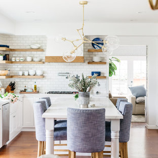 Inspiration for a mid-sized transitional u-shaped medium tone wood floor and brown floor eat-in kitchen remodel in Los Angeles with a farmhouse sink, recessed-panel cabinets, white cabinets, white backsplash, subway tile backsplash, stainless steel appliances, an island, white countertops and quartzite countertops