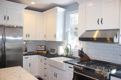 Inspiration for a cottage medium tone wood floor kitchen remodel in Philadelphia with a farmhouse sink, shaker cabinets, white cabinets, soapstone countertops, white backsplash, subway tile backsplash, stainless steel appliances and an island