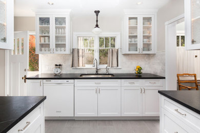 Example of a mid-sized farmhouse galley ceramic tile enclosed kitchen design in Los Angeles with a double-bowl sink, shaker cabinets, white cabinets, soapstone countertops, stone tile backsplash, stainless steel appliances, no island and white backsplash