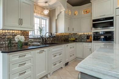Example of a large transitional u-shaped travertine floor eat-in kitchen design in Milwaukee with an undermount sink, flat-panel cabinets, white cabinets, quartzite countertops, metallic backsplash, glass tile backsplash, paneled appliances and an island