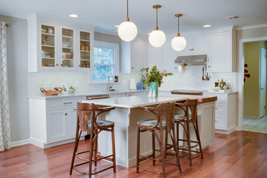 Example of a large transitional u-shaped light wood floor eat-in kitchen design in Philadelphia with an undermount sink, shaker cabinets, white cabinets, quartzite countertops, multicolored backsplash, glass tile backsplash, stainless steel appliances and an island