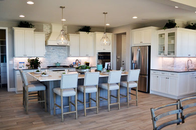Example of a large transitional l-shaped porcelain tile and brown floor open concept kitchen design in Denver with an island, an undermount sink, white backsplash, marble backsplash, stainless steel appliances, recessed-panel cabinets and white cabinets