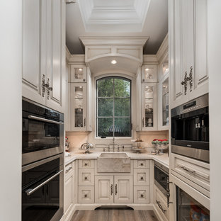 Immagine di un'ampia cucina ad U stile shabby chiusa con lavello stile country, ante con bugna sagomata, ante in legno chiaro, top in quarzite, paraspruzzi beige, paraspruzzi in gres porcellanato, elettrodomestici in acciaio inossidabile, pavimento in legno massello medio, nessuna isola, pavimento marrone e top beige