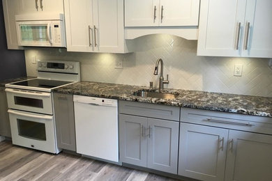 Example of a mid-sized transitional single-wall vinyl floor eat-in kitchen design in New York with an undermount sink, shaker cabinets, white cabinets, granite countertops, white backsplash, subway tile backsplash, white appliances and an island