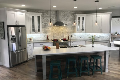 Large transitional single-wall light wood floor and gray floor eat-in kitchen photo in Atlanta with a farmhouse sink, shaker cabinets, white cabinets, quartzite countertops, white backsplash, marble backsplash, stainless steel appliances and white countertops