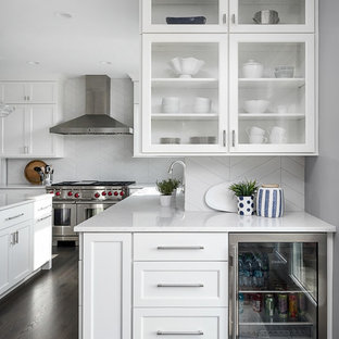 Foto de cocina clásica renovada, grande, con puertas de armario blancas, salpicadero blanco, salpicadero de azulejos de porcelana, electrodomésticos de acero inoxidable, una isla, encimeras blancas, armarios tipo vitrina, suelo de madera oscura, encimera de cuarcita y suelo marrón