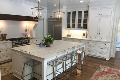 Large transitional u-shaped dark wood floor and brown floor eat-in kitchen photo in Other with recessed-panel cabinets, white cabinets, marble countertops, white backsplash, subway tile backsplash, stainless steel appliances, an island, white countertops and an undermount sink