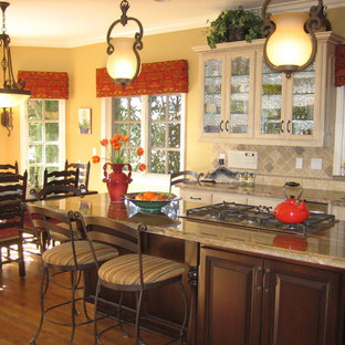 Photo of a traditional eat-in kitchen in Los Angeles with glass-front cabinets, beige cabinets and beige splashback.