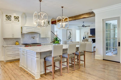 Bild på ett stort vintage linjärt kök och matrum, med skåp i shakerstil, vita skåp, marmorbänkskiva, grått stänkskydd, stänkskydd i stickkakel, rostfria vitvaror, ljust trägolv, en köksö och brunt golv
