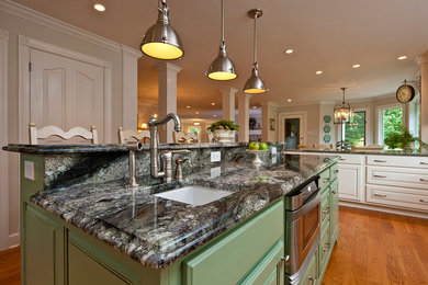 Example of a large transitional u-shaped medium tone wood floor eat-in kitchen design in Philadelphia with an undermount sink, raised-panel cabinets, green cabinets, granite countertops, beige backsplash, stone tile backsplash and stainless steel appliances