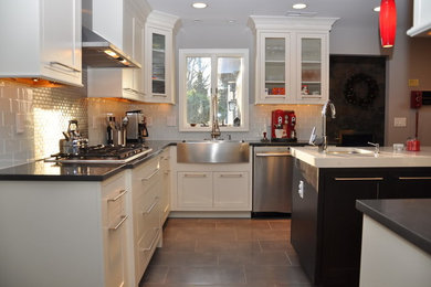Photo of a medium sized rural l-shaped kitchen/diner in New York with a belfast sink, shaker cabinets, white cabinets, grey splashback, porcelain splashback, stainless steel appliances, ceramic flooring, an island and grey floors.