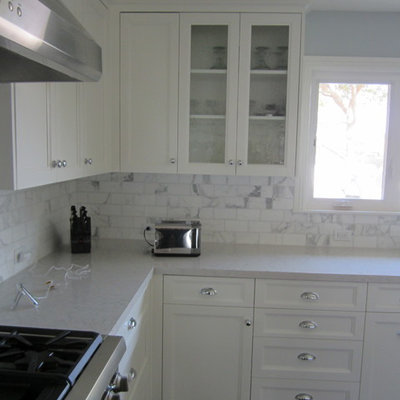 Eat-in kitchen - mid-sized transitional u-shaped eat-in kitchen idea in Los Angeles with a farmhouse sink, shaker cabinets, white cabinets, quartzite countertops, white backsplash, stone tile backsplash and stainless steel appliances
