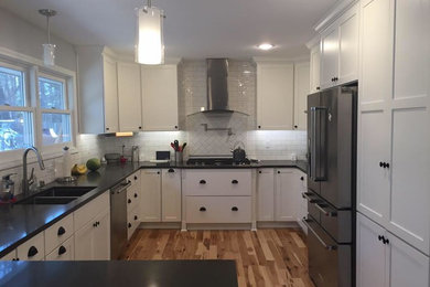 ミルウォーキーにある中くらいなトランジショナルスタイルのおしゃれなキッチン (白いキャビネット、白いキッチンパネル、サブウェイタイルのキッチンパネル、シルバーの調理設備、無垢フローリング、アイランドなし) の写真