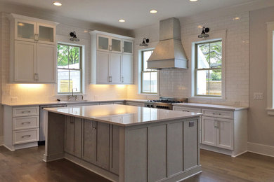Example of a transitional medium tone wood floor kitchen design in Charleston with an undermount sink, white cabinets, white backsplash, subway tile backsplash, stainless steel appliances and an island