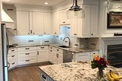 Large transitional u-shaped light wood floor and brown floor open concept kitchen photo with an undermount sink, flat-panel cabinets, white cabinets, granite countertops, stainless steel appliances and an island