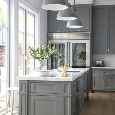 Inspiration for a transitional light wood floor kitchen remodel in Houston with an undermount sink, recessed-panel cabinets, gray cabinets, white backsplash, subway tile backsplash, stainless steel appliances, an island and white countertops