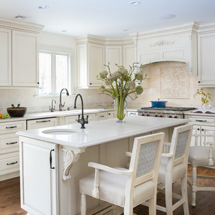 Inspiration for a large traditional u-shaped eat-in kitchen in Newark with an undermount sink, beige splashback, medium hardwood floors, with island, brown floor, recessed-panel cabinets, beige cabinets, quartz benchtops, marble splashback, panelled appliances and beige benchtop.