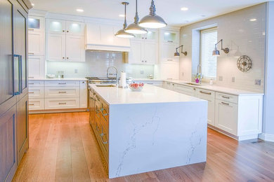 Inspiration for a mid-sized transitional u-shaped medium tone wood floor and brown floor kitchen remodel in Calgary with an undermount sink, flat-panel cabinets, white cabinets, marble countertops, gray backsplash, ceramic backsplash, paneled appliances and an island