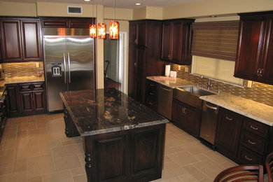Cette image montre une cuisine américaine traditionnelle avec un évier de ferme, des portes de placard marrons, un plan de travail en granite, une crédence beige et une crédence en carreau de verre.