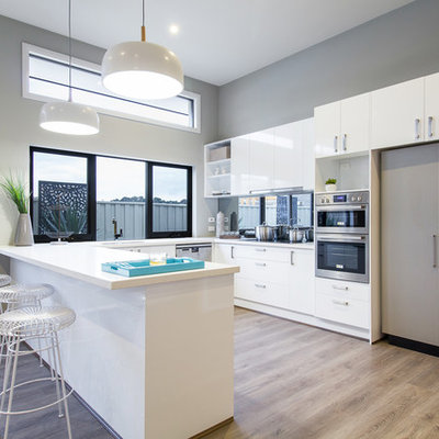 Kitchen - transitional u-shaped light wood floor kitchen idea in Other with flat-panel cabinets, white cabinets, paneled appliances and a peninsula