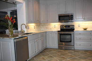 Inredning av ett klassiskt mellanstort l-kök, med en undermonterad diskho, luckor med upphöjd panel, vita skåp, granitbänkskiva, beige stänkskydd, stänkskydd i stenkakel, rostfria vitvaror, klinkergolv i porslin och en halv köksö