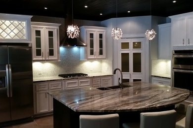 Example of a mid-sized transitional l-shaped porcelain tile open concept kitchen design in Houston with a farmhouse sink, glass-front cabinets, white cabinets, granite countertops, gray backsplash, stone tile backsplash, stainless steel appliances and an island