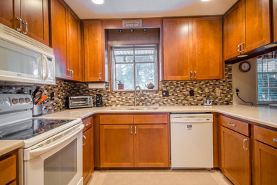 Mid-sized transitional u-shaped ceramic tile eat-in kitchen photo in Jacksonville with medium tone wood cabinets, white appliances, a double-bowl sink, shaker cabinets, solid surface countertops, multicolored backsplash, mosaic tile backsplash and a peninsula