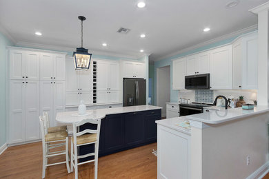 Exempel på ett stort klassiskt vit vitt kök, med vita skåp, bänkskiva i kvarts, en köksö, en undermonterad diskho, luckor med infälld panel, flerfärgad stänkskydd, stänkskydd i mosaik, rostfria vitvaror, mellanmörkt trägolv och brunt golv