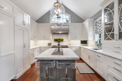 Kitchen - large transitional medium tone wood floor and brown floor kitchen idea in New York with an undermount sink, raised-panel cabinets, white cabinets, marble countertops, white backsplash, marble backsplash, paneled appliances, an island and white countertops