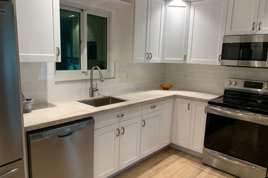 Inspiration for a medium sized traditional l-shaped kitchen in Miami with a submerged sink, shaker cabinets, white cabinets, limestone worktops, white splashback, metro tiled splashback, stainless steel appliances, light hardwood flooring, no island and beige worktops.