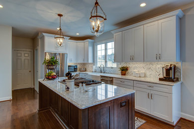Example of a mid-sized transitional u-shaped dark wood floor and brown floor eat-in kitchen design in DC Metro with a farmhouse sink, shaker cabinets, white cabinets, stainless steel appliances, an island, gray countertops, quartzite countertops, white backsplash and mosaic tile backsplash