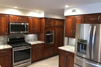 Photo of a medium sized traditional l-shaped enclosed kitchen in Other with raised-panel cabinets, medium wood cabinets, soapstone worktops, grey splashback, mosaic tiled splashback, stainless steel appliances, light hardwood flooring, no island and brown floors.