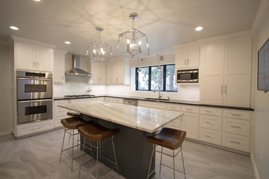 Mid-sized transitional l-shaped porcelain tile and gray floor enclosed kitchen photo in Dallas with a single-bowl sink, shaker cabinets, white cabinets, quartzite countertops, white backsplash, subway tile backsplash, stainless steel appliances and an island