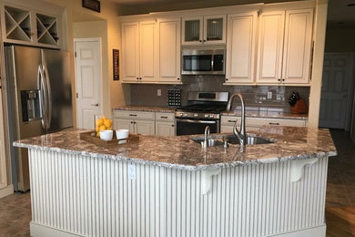 Example of a mid-sized transitional eat-in kitchen design in Denver with an undermount sink, raised-panel cabinets, beige cabinets, granite countertops, beige backsplash, subway tile backsplash, stainless steel appliances and an island