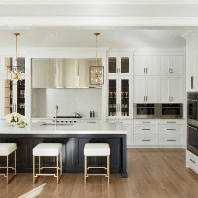 Example of a mid-sized transitional l-shaped light wood floor and gray floor eat-in kitchen design in Chicago with an undermount sink, white cabinets, quartz countertops, white backsplash, stone slab backsplash, stainless steel appliances, an island, white countertops and shaker cabinets
