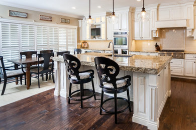 Kitchen - large transitional l-shaped kitchen idea in St Louis with an undermount sink, raised-panel cabinets, white cabinets, granite countertops, beige backsplash, subway tile backsplash, stainless steel appliances and an island