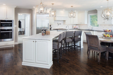 Eat-in kitchen - large transitional l-shaped dark wood floor and brown floor eat-in kitchen idea in New York with an undermount sink, raised-panel cabinets, white cabinets, marble countertops, gray backsplash, marble backsplash, stainless steel appliances, an island and white countertops