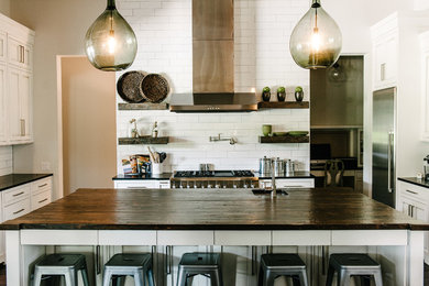 Transitional kitchen photo in Austin with an undermount sink, recessed-panel cabinets, white cabinets, wood countertops, white backsplash, subway tile backsplash, stainless steel appliances and an island