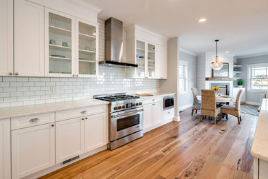 Eat-in kitchen - large transitional l-shaped medium tone wood floor eat-in kitchen idea in Philadelphia with an undermount sink, shaker cabinets, white cabinets, marble countertops, white backsplash, subway tile backsplash, stainless steel appliances and an island